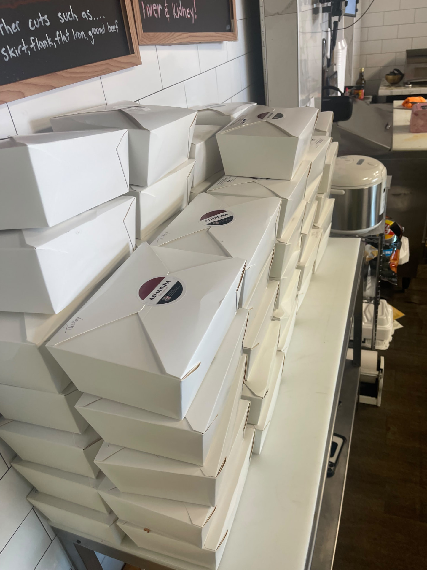 Stacks of Asmarina-branded white catering boxes packed and ready